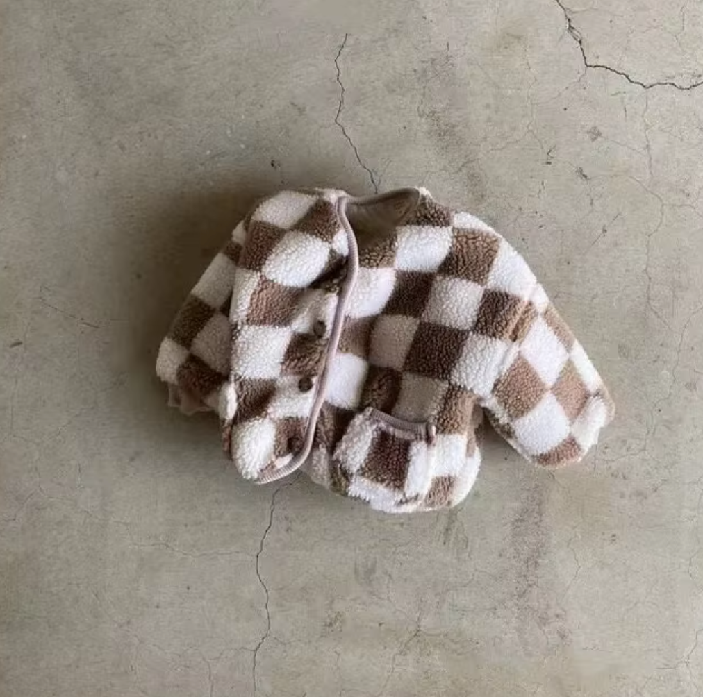 Checkered baby jacket on a textured concrete surface