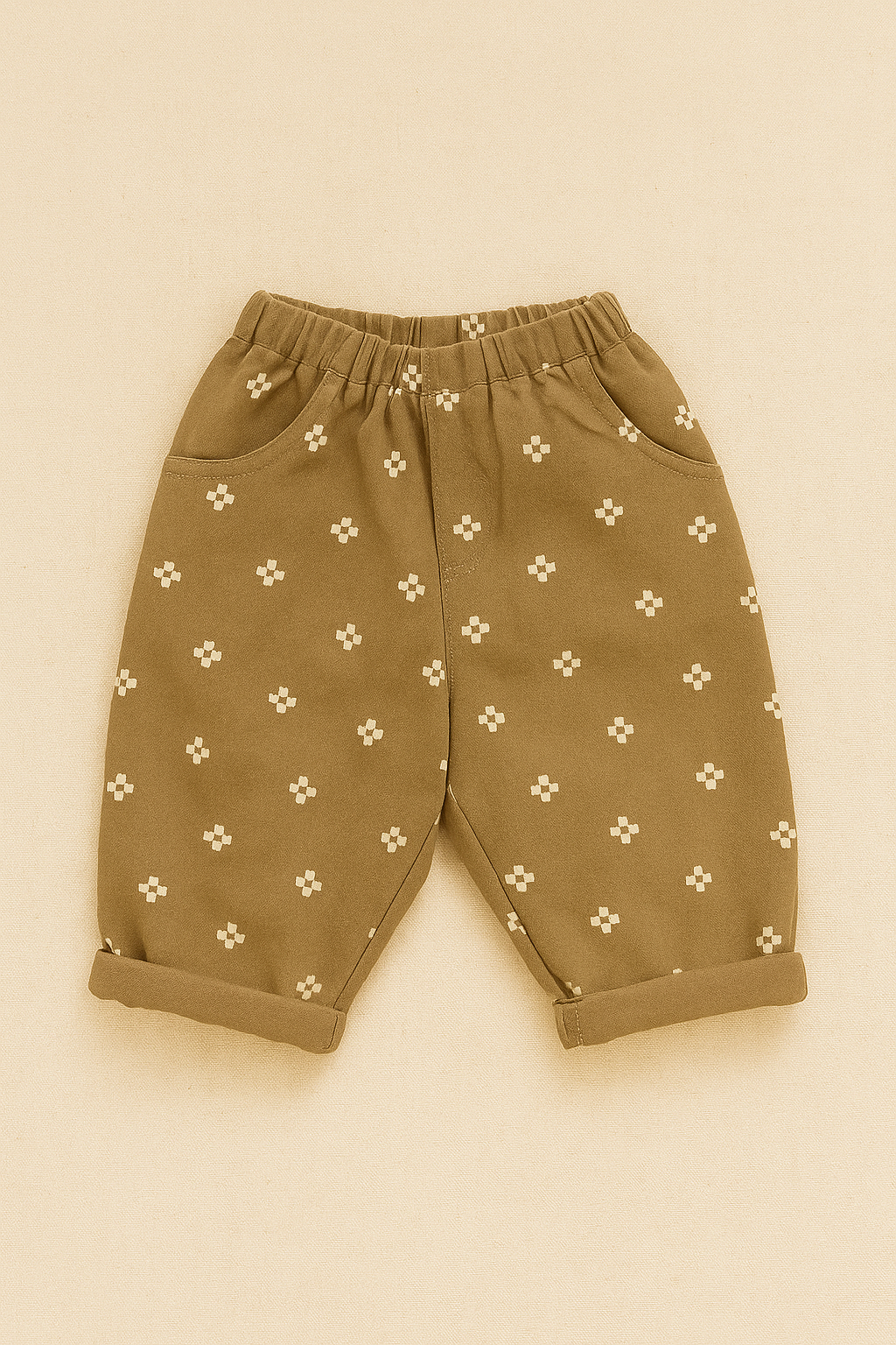 Beige baby pants with white floral pattern on a beige background