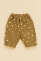 Beige baby pants with white floral pattern on a beige background