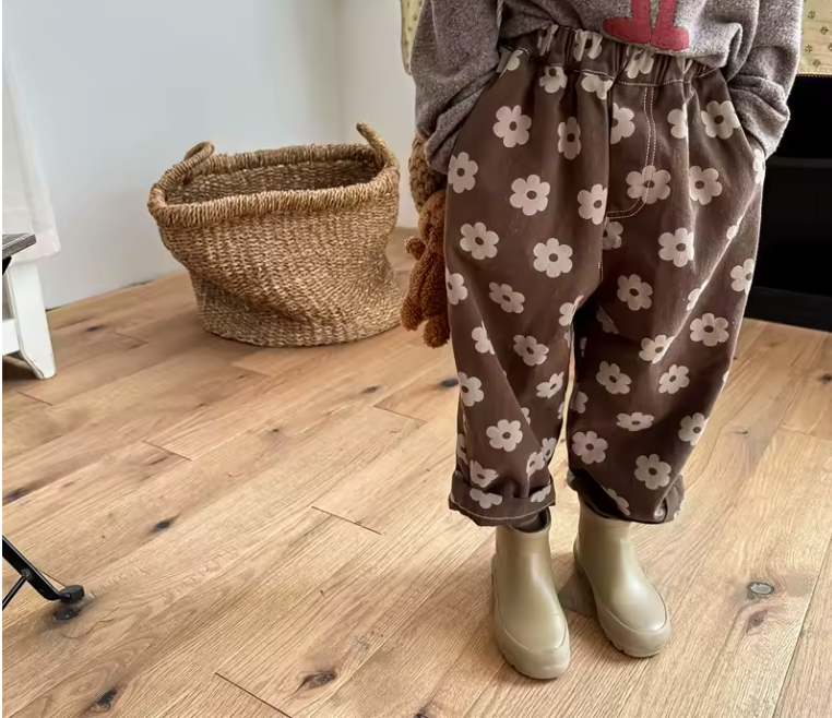 Brown children's pants with flower pattern on a beige background